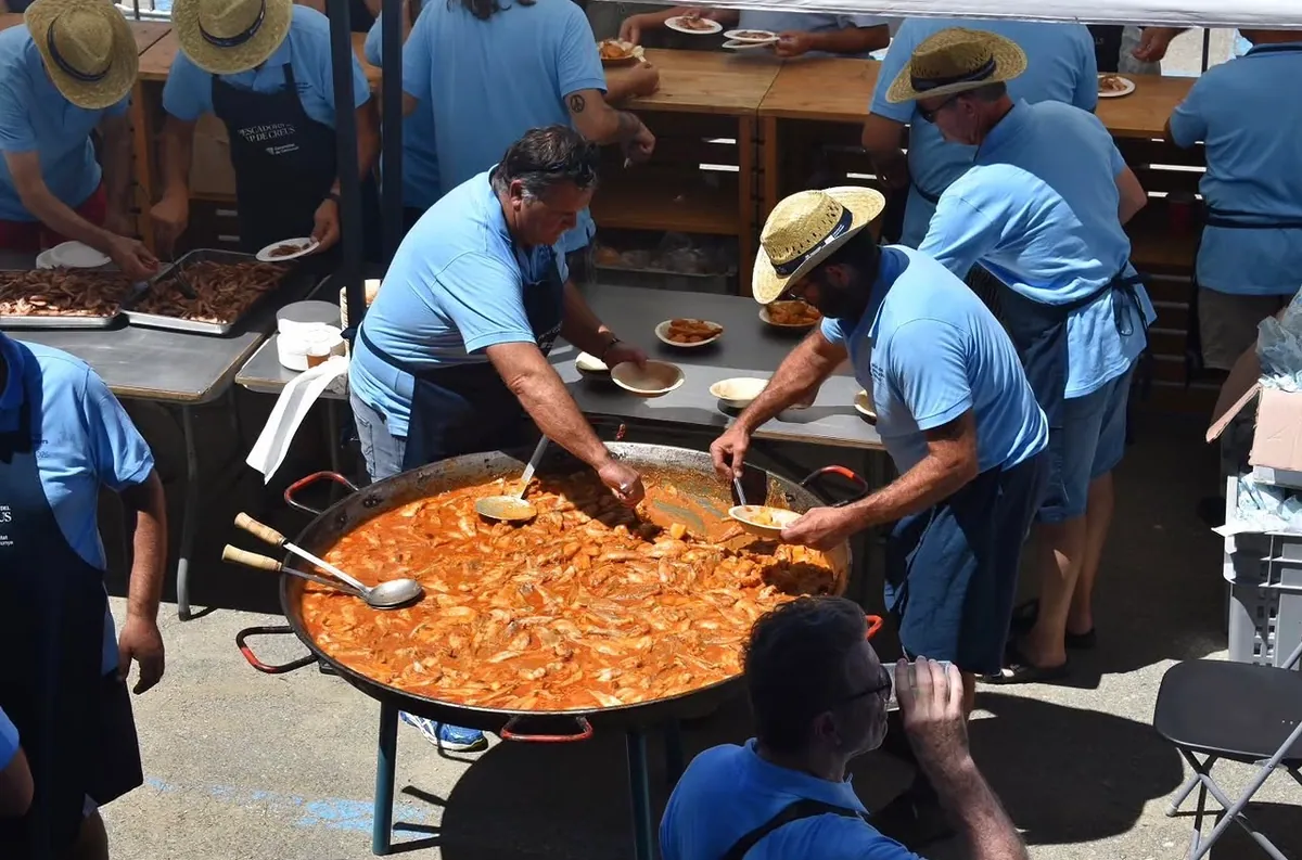 Des pêcheurs remuent le suquet de poisson dans une grande marmite sur le port